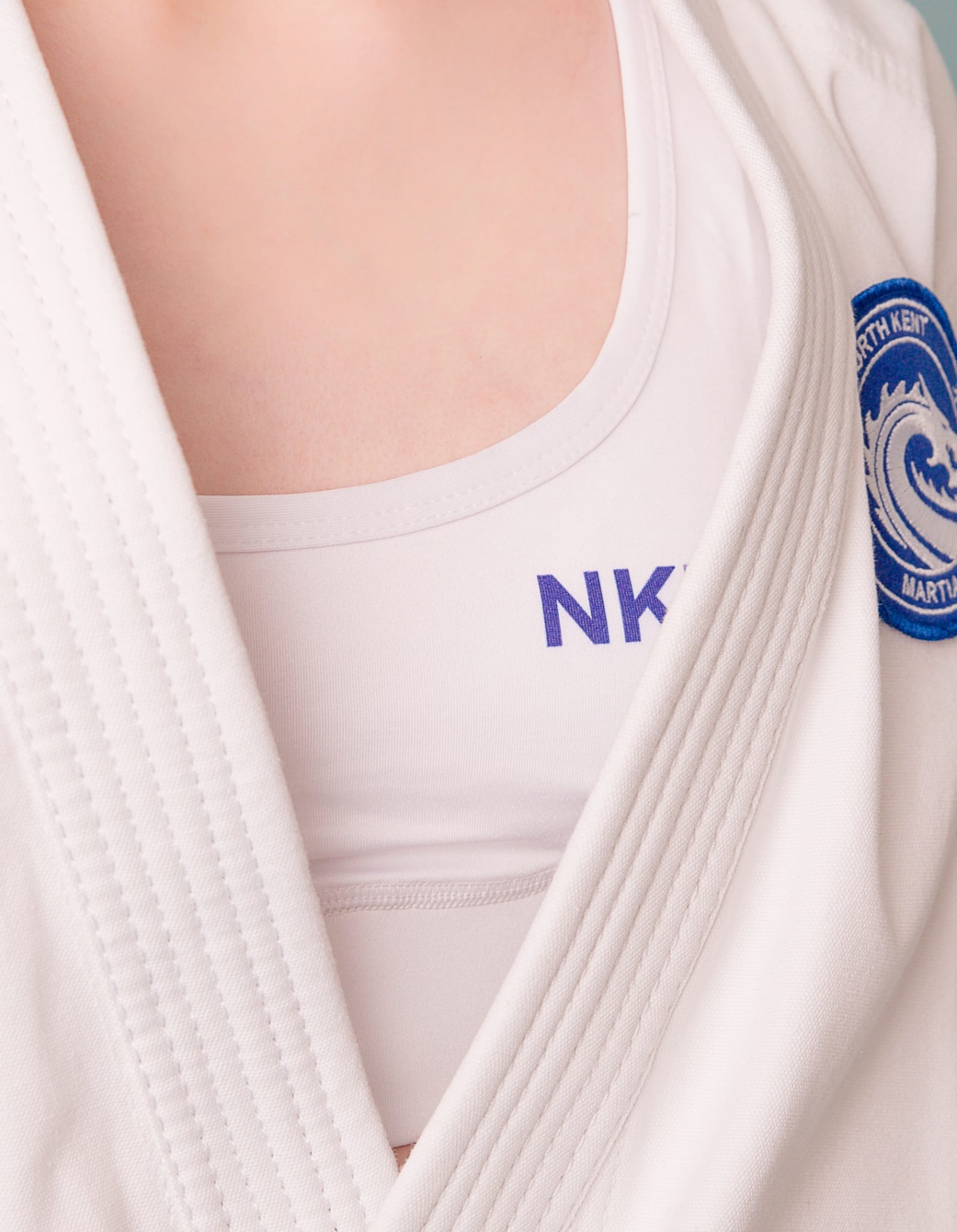 nkma white under gi crop top close up worn on female model wearing gi